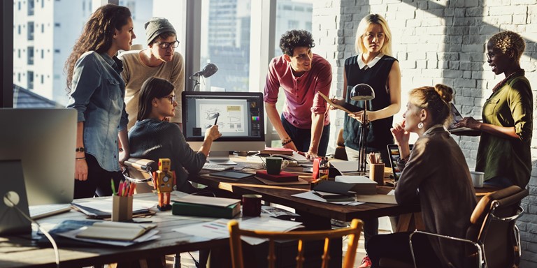 Employees gathered round a cluttered workspace